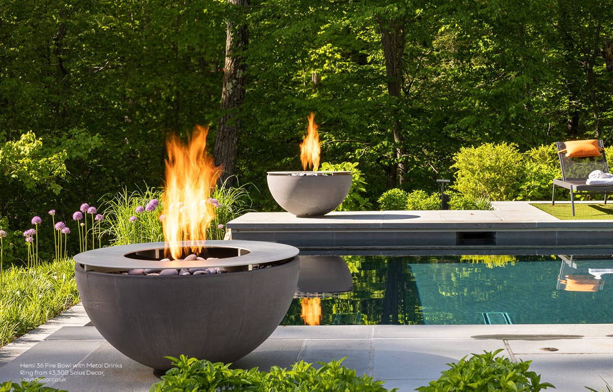 Hemi 36 fire bowl with metal drinks ring beside a contemporary outdoor swimming pool surrounded by woodland.
